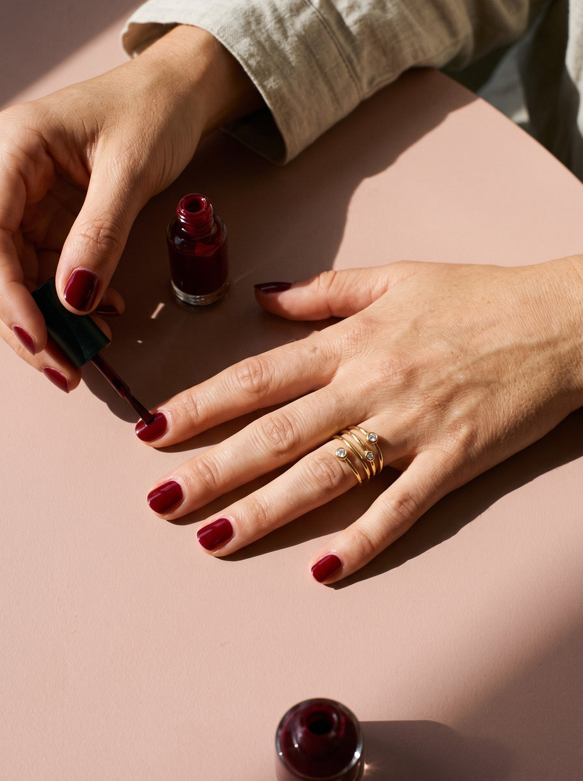 Lundholm Alexia verstelbare ring met zirkonia goudkleurig gedragen, hand met bordeauxrode nagellak
