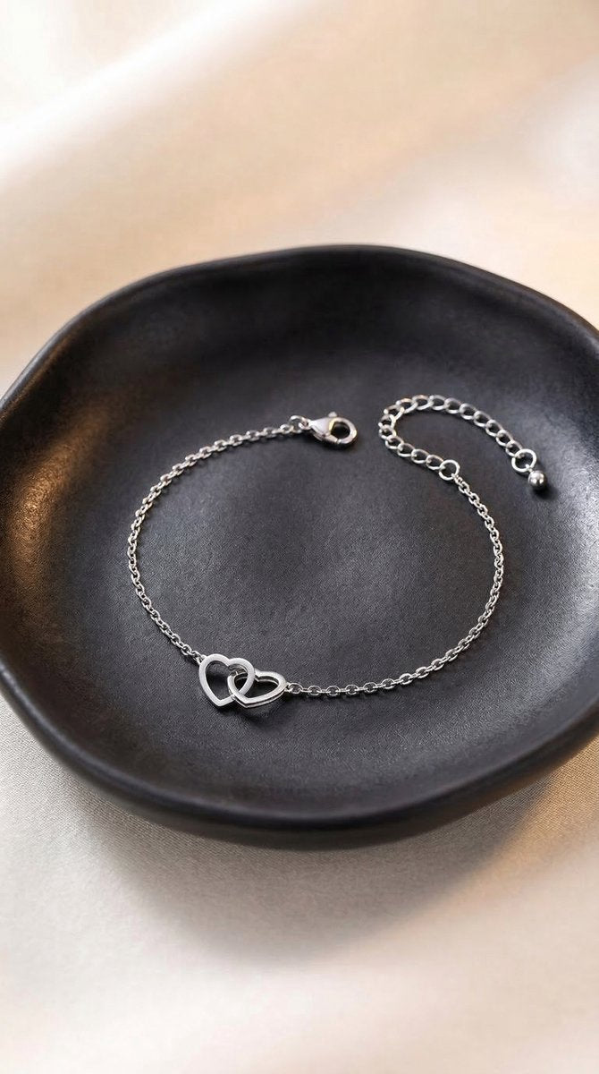 Lundholm Alice armband zilverkleurig met verstrengelde hartjes op zwart keramiek schaaltje, sfeerbeeld minimalistisch sieraad