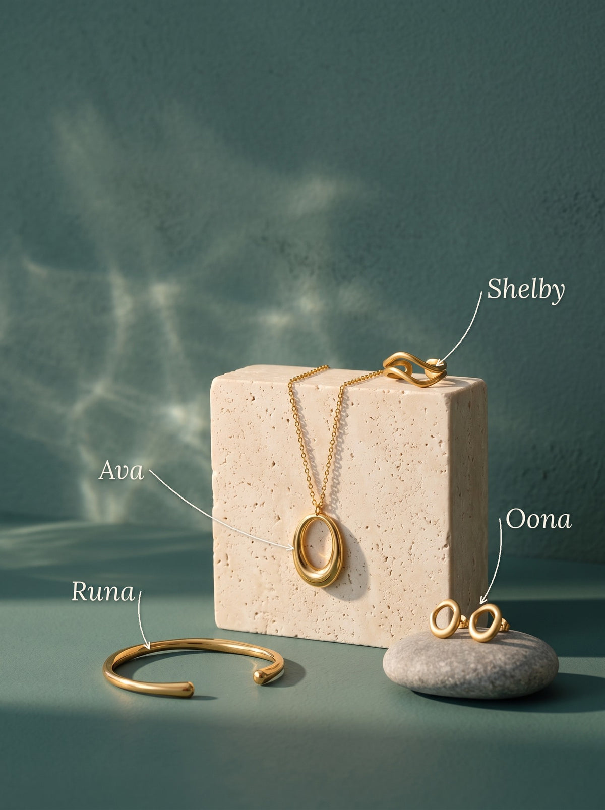 Lundholm Ava ketting met open ovale hanger, Shelby ring met dubbele golf, Oona organische ovale oorknopjes en Runa open bangle goudkleurig bij een blok travertin en een kiezelsteen