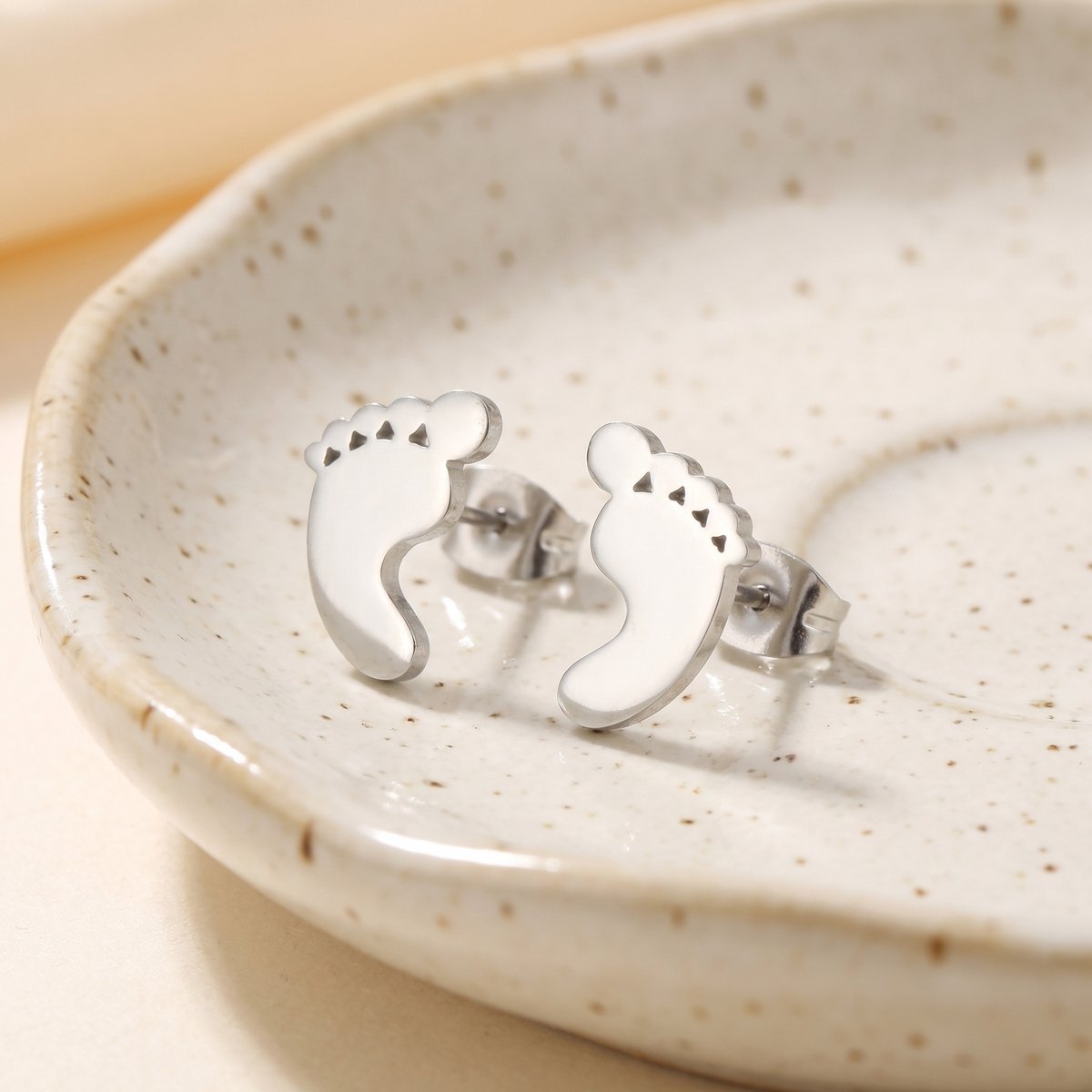 Lundholm Bebe babyvoetjes oorknopjes in zilver, sfeerfoto op keramieken schaaltje, cadeau voor moederdag