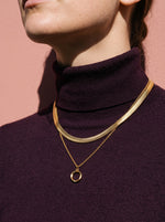 Lundholm Bo ketting met open ronde hanger goudkleurig gedragen op een pruimkleurige coltrui