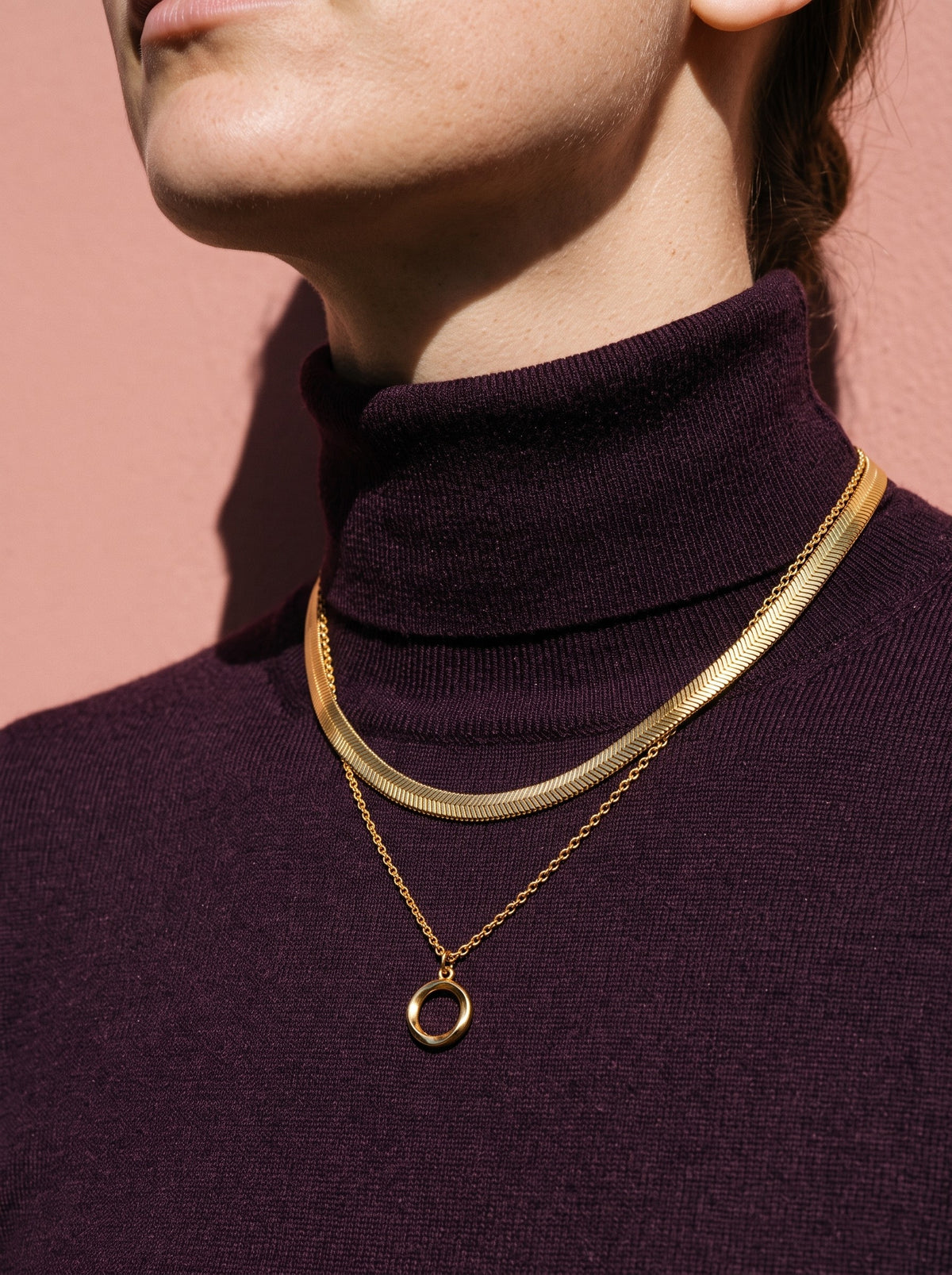 Lundholm Bo ketting met open ronde hanger goudkleurig gedragen op een pruimkleurige coltrui