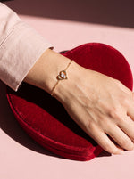 Lundholm Cara open hartjes armband met zirkonia goudkleurig gedragen, hand op een hartvormige bonbondoos