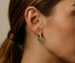 Lundholm My Delia creolen oorringen met zirkonia steentjes in goudkleurig 18mm, gedragen aan vrouwenoor