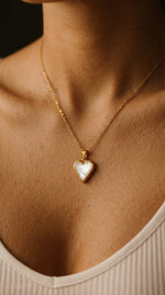 Lundholm Dory ketting met goudkleurige hartjes hanger en parelmoer gedragen door model, romantisch sieraad cadeau voor vrouwen