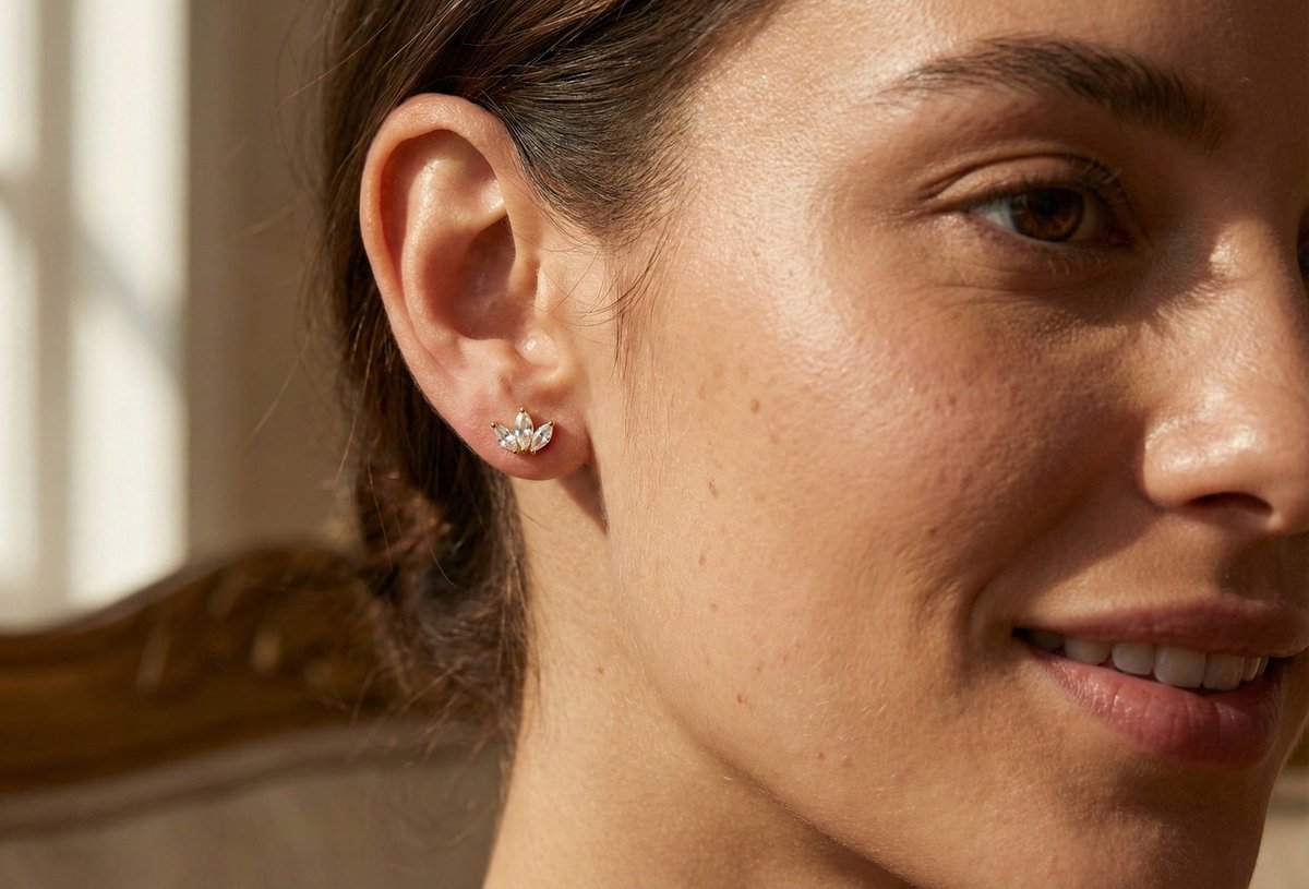 Lundholm Elara zirkonia studs oorknopjes lotus design in goudkleurig, gedragen aan vrouwenoor