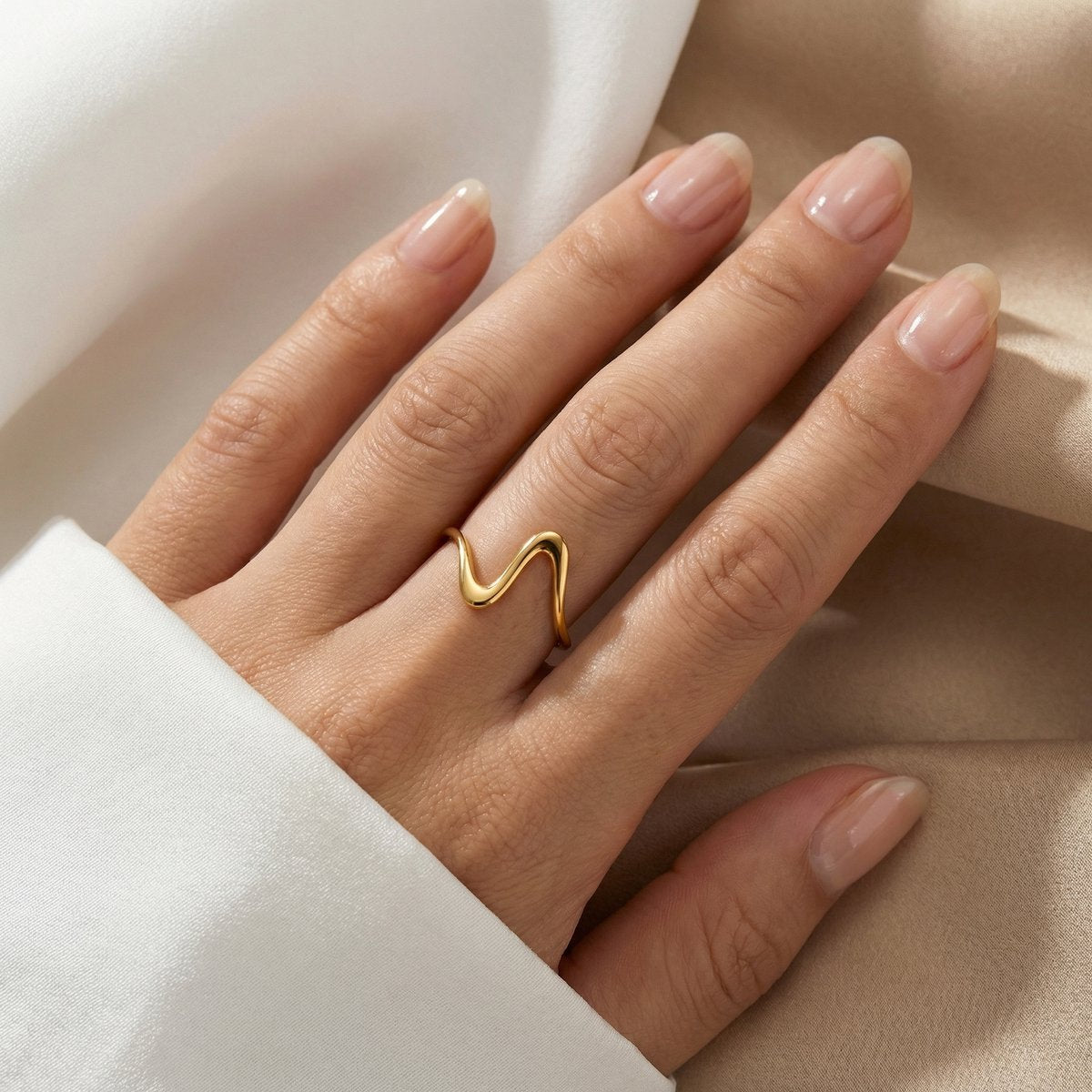 Lundholm Elia ring goudkleurig minimalistisch golfvorm verstelbaar gedragen aan vinger op zijde, modern sieraad cadeau voor vrouwen