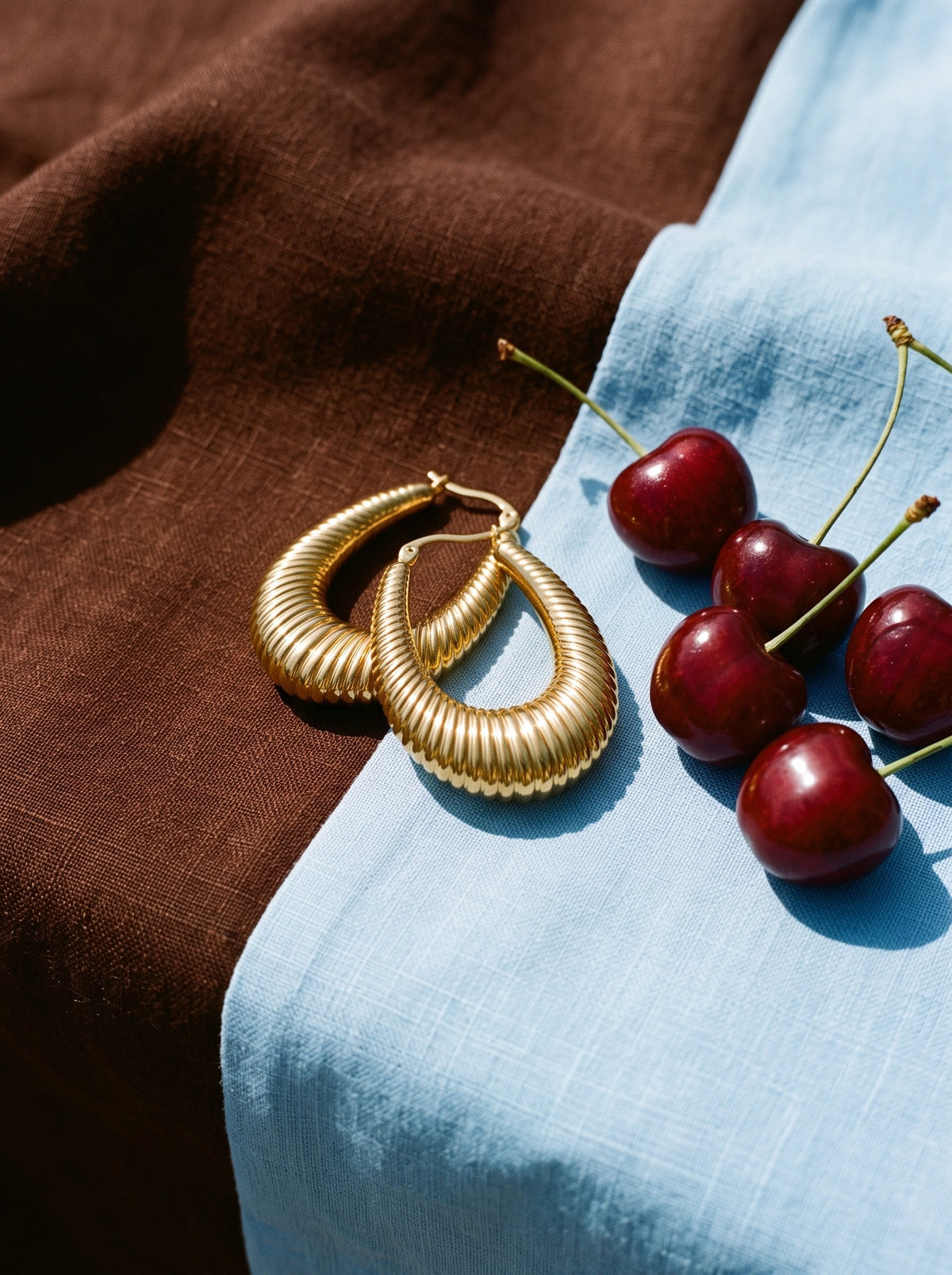 Lundholm Elin grote statement hoops goudkleurig op linnen naast verse kersen