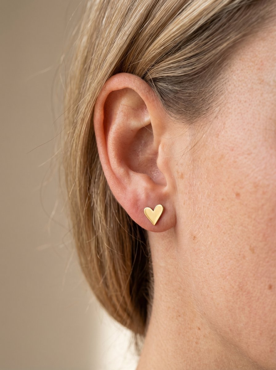 Vrouw draagt Lundholm Femme hartje stud oorknopje in goudkleurig stainless steel