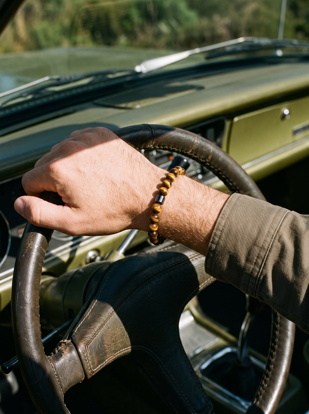 Man draagt de Lundholm Gunnar herenarmband met tijgeroog kralen aan het stuur van een klassieke auto
