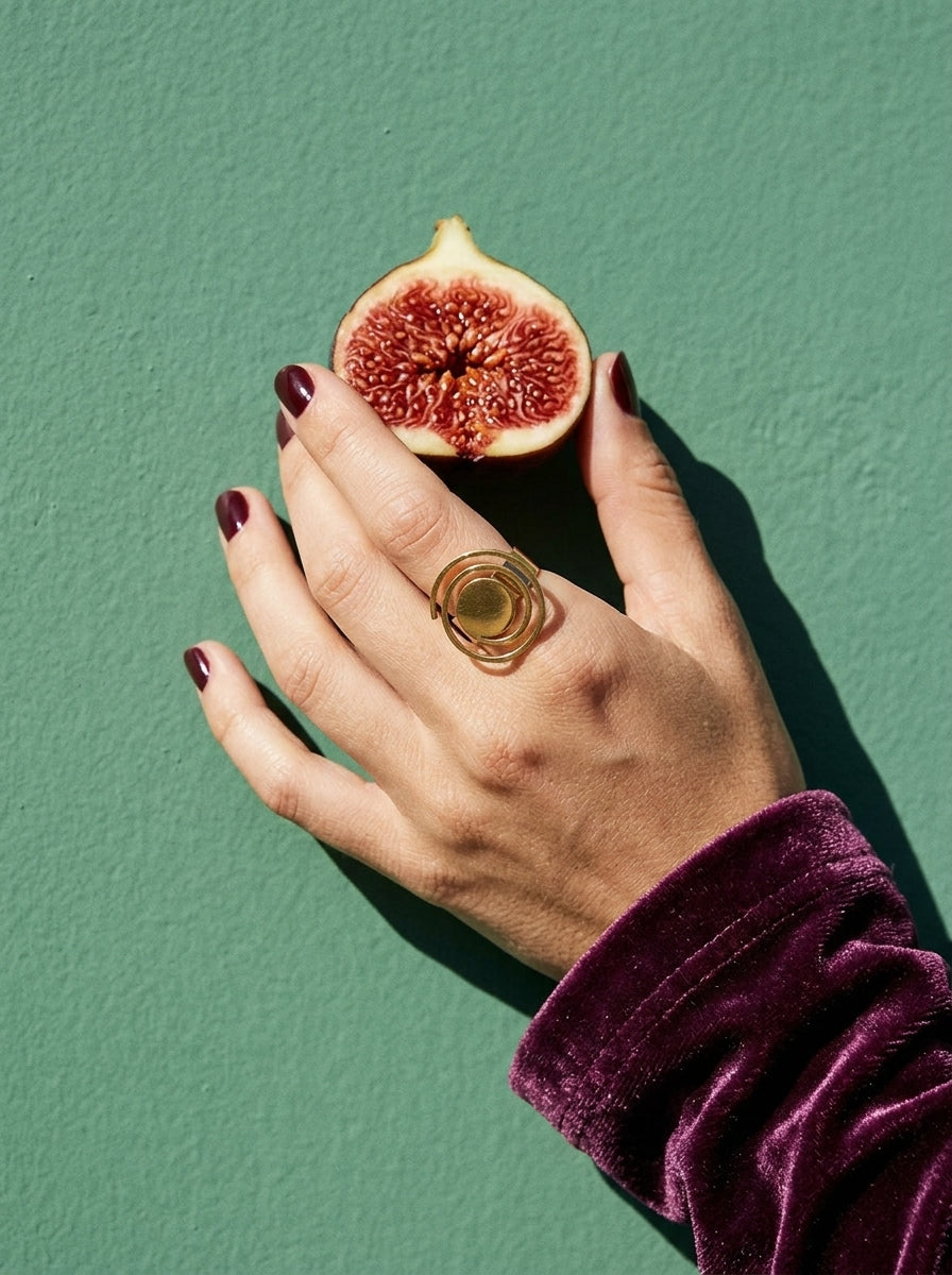 Lundholm Jiva grote statement ring goudkleurig gedragen, hand met verse vijg