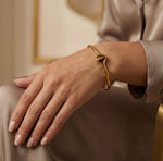 Lundholm Jol open bangle armband met tijgeroog steen in goudkleurig, gedragen aan vrouwenpols, lifestyle