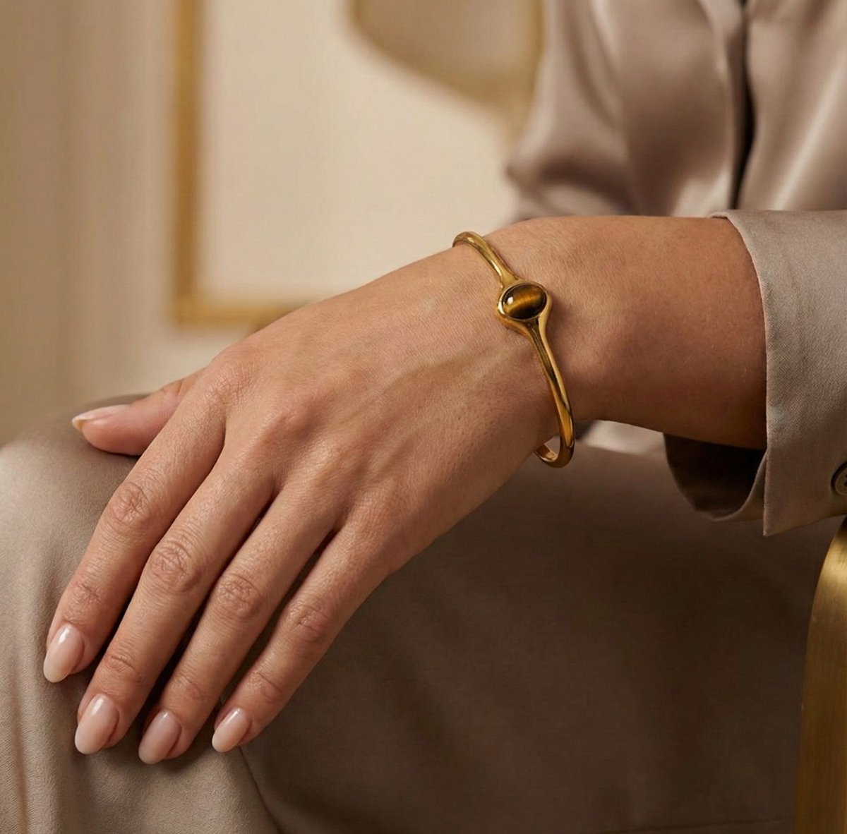 Lundholm Jol open bangle armband met tijgeroog steen in goudkleurig, gedragen aan vrouwenpols, lifestyle