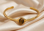 Lundholm Jol open bangle armband met tijgeroog steen in goudkleurig op satijn, productfoto Scandinavisch design