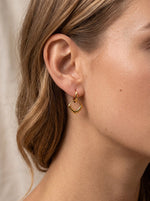 Vrouw draagt Lundholm Julia goud oorbel op het oor — Scandinavisch design statement vierkante hanger