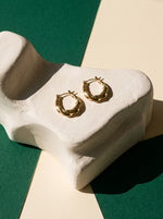 Lundholm Lexi chunky gedraaide oorringen goudkleurig op een witte gipsen sculptuur