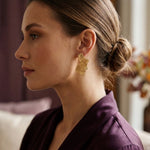 Lundholm Linden ginkgo oorbel goudkleurig gedragen bij een plum satijnen blouse