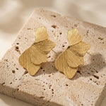 Lundholm Linden ginkgo blad oorbellen goudkleurig op travertin, twee identieke oorstekers