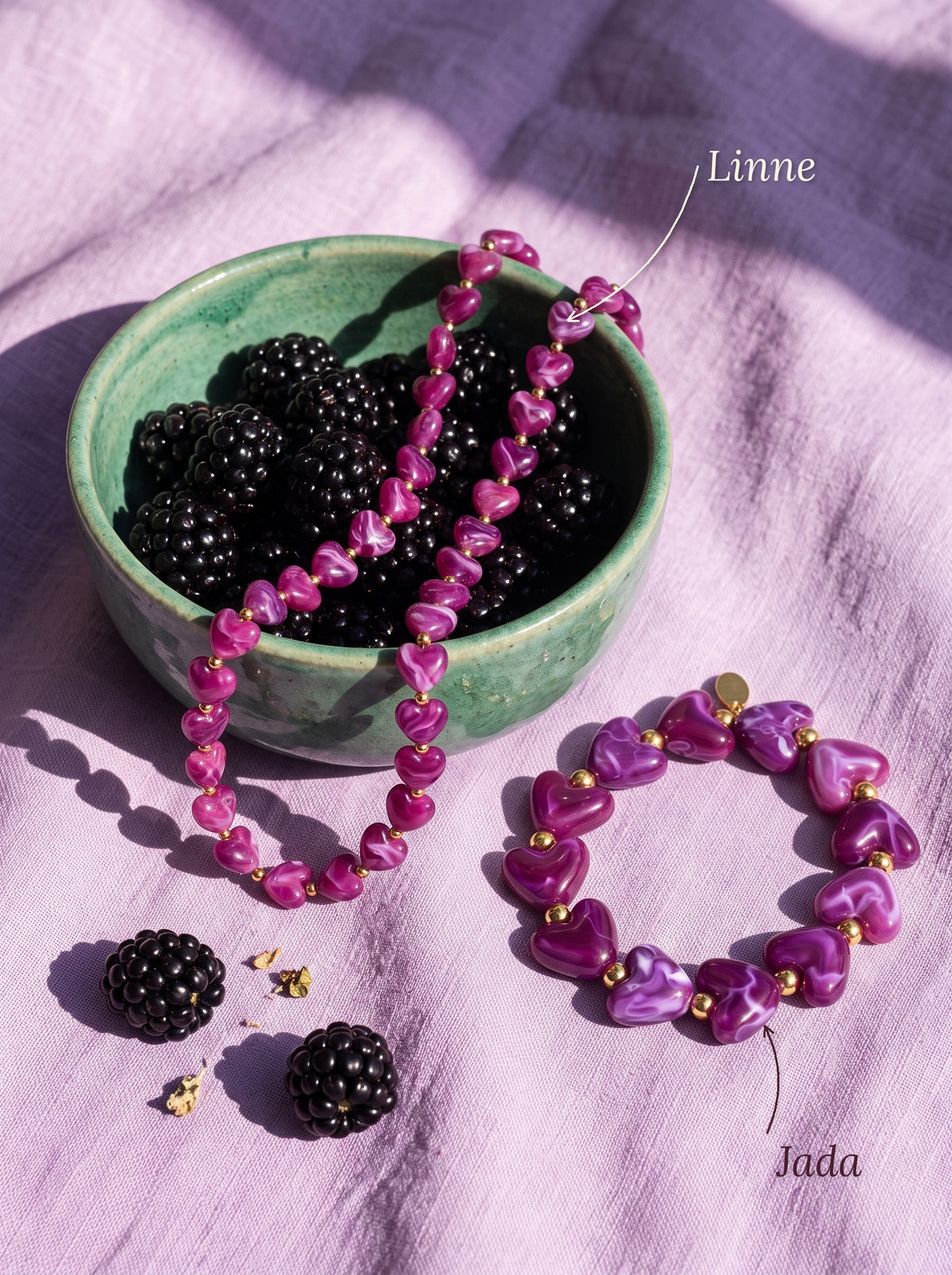 Lundholm Linne kralenketting en Jada kralenarmband paars met hartjes, met hun namen erbij, bij een schaaltje bramen