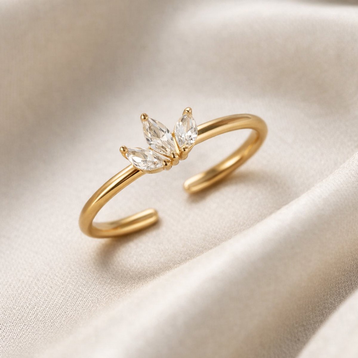Lundholm Lotus ring met drie zirkonia steentjes in goudkleurig verstelbaar, close-up productfoto op satijn