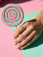 Lundholm Lou open ring met spiraal reliëf goudkleurig gedragen, hand met een lolly