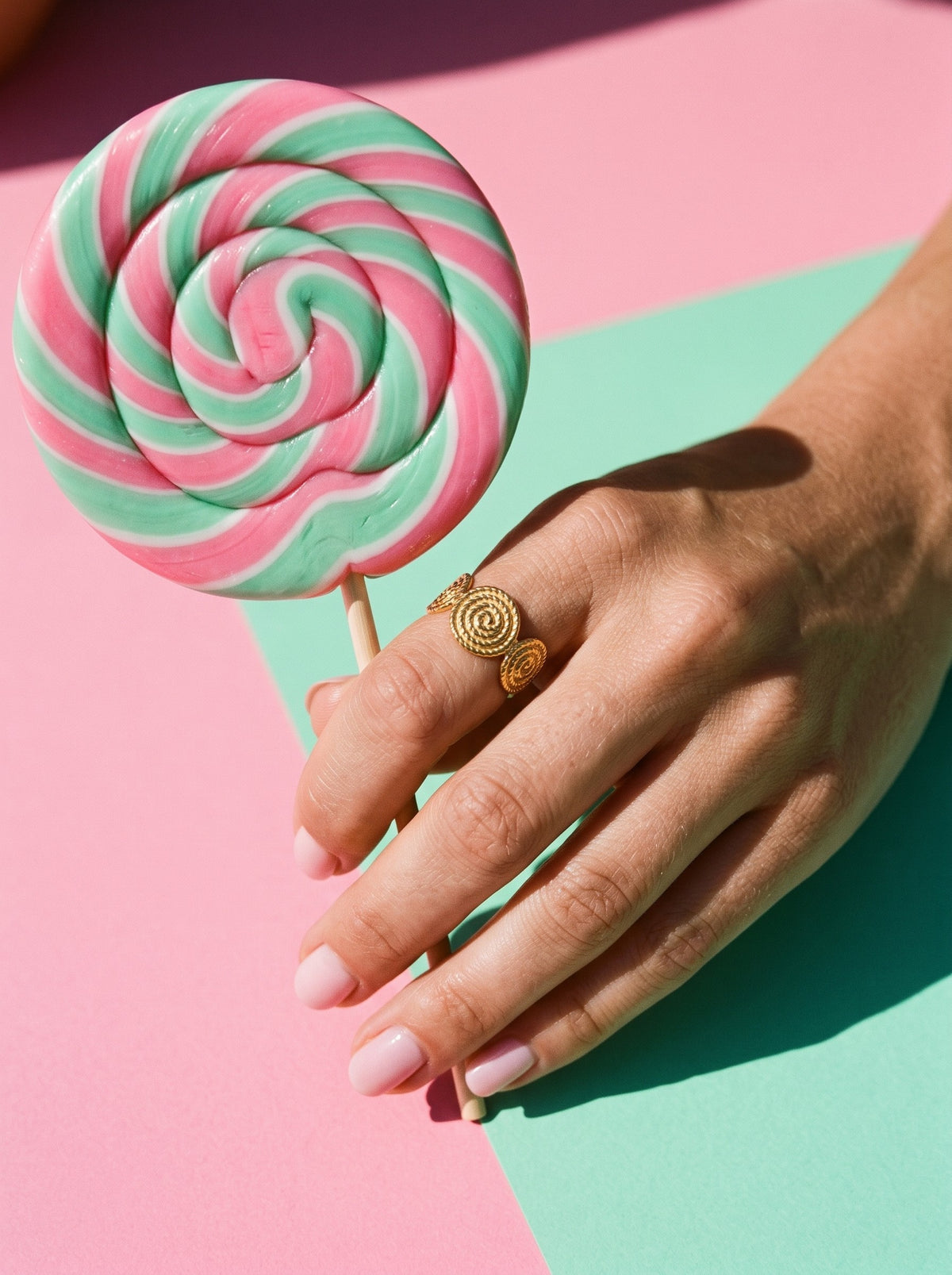 Lundholm Lou open ring met spiraal reliëf goudkleurig gedragen, hand met een lolly