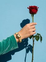 Lundholm Lova bangle met hart goudkleurig gedragen, hand met rode roos