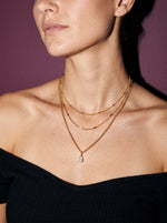 Vrouw draagt de Lundholm Lucille drielaagse ketting met zirkonia druppel goudkleurig