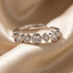 Close-up van de ronde en ruitvormige zirkonia zettingen van de Lundholm Lumi ring op satijn
