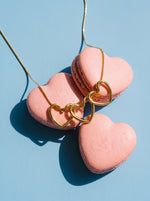 Lundholm Luv ketting met drie hartjes goudkleurig over roze hartjesmacarons