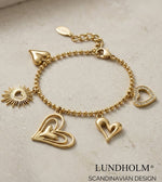 Lundholm luxe schakelarmband My Love met hartjes bedels in goudkleurig op lichte ondergrond, lifestyle