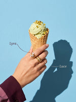 Lundholm Lyra wikkelring en Luce drievoudige ring met zirkonia goudkleurig gedragen, met hun namen erbij, hand met pistache-ijsje