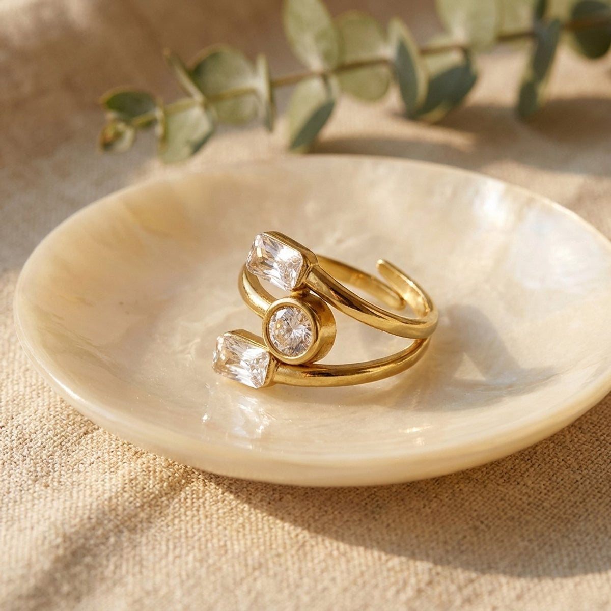Lundholm Lyra goudkleurige zirkonia ring in een schaaltje met eucalyptus – cadeau voor haar