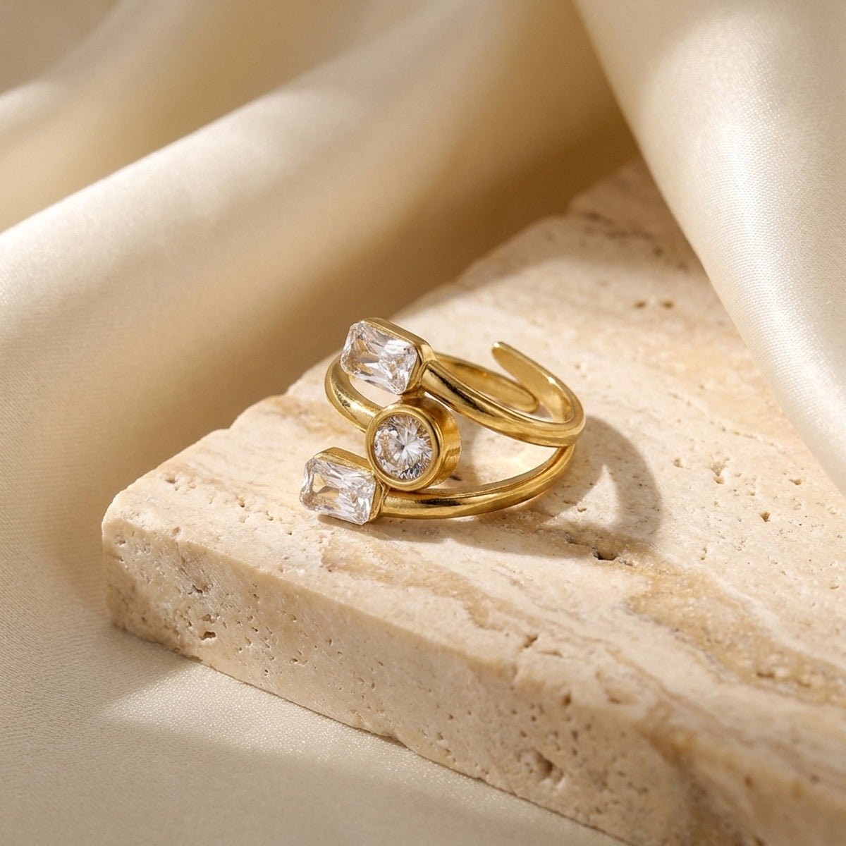 Lundholm Lyra gouden wikkelring met drie zirkonia steentjes op natuursteen – Scandinavisch design
