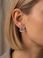 Lundholm Macey oorbellen zilver driehoek studs gedragen aan vrouwenoor — minimalistisch Scandinavisch design