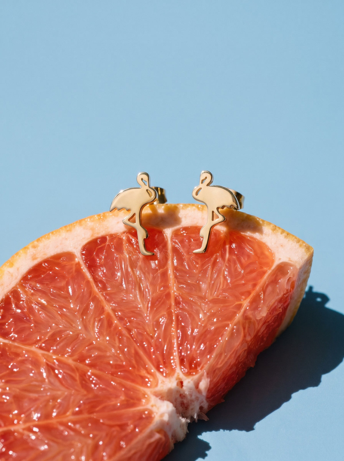 Lundholm Mingo flamingo oorknopjes goudkleurig op een halve grapefruit