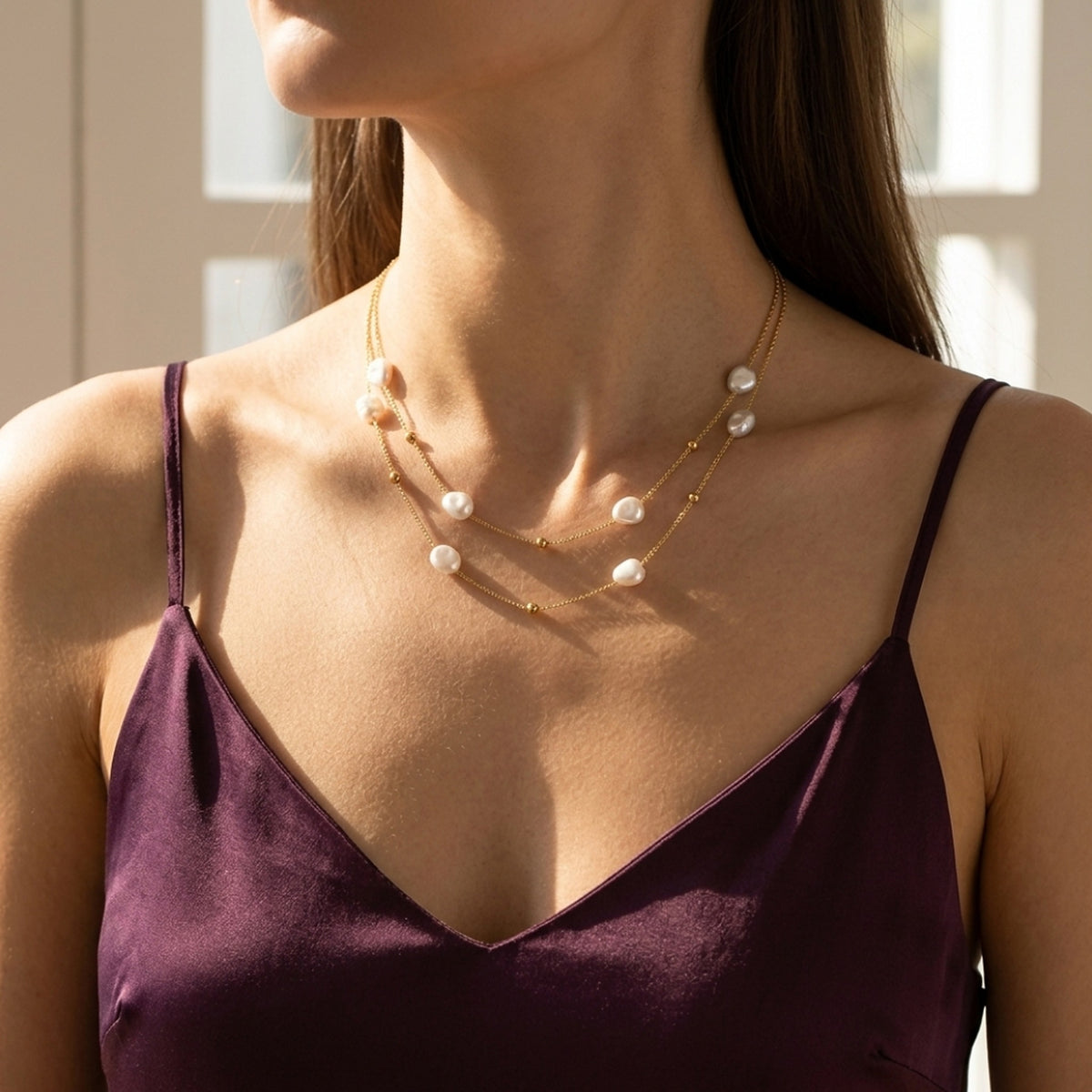 Lundholm Mirabelle layered parelketting goudkleurig gedragen bij een pruimkleurige satijnen top