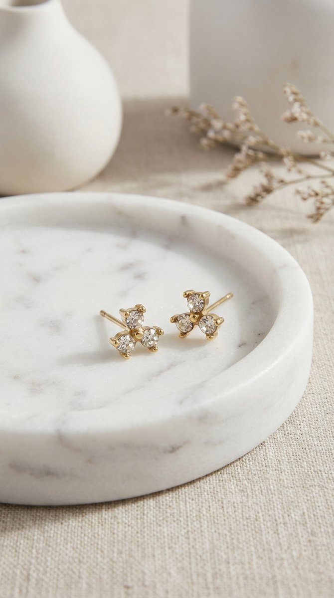 Lundholm zirkonia oorknopjes met cluster steentjes in goudkleurig op marmeren schaaltje, sfeervolle styling