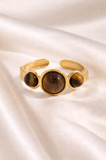Lundholm Orion verstelbare statement ring met drie tijgeroog stenen in goudkleurig op satijn, productfoto