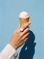 Lundholm Philippa statement ring met witte parelmoer goudkleurig gedragen, hand met een ijshoorntje