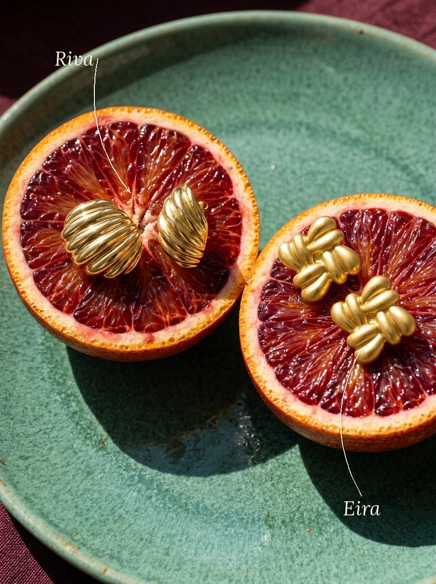Lundholm Riva en Eira statement oorknopjes goudkleurig, met hun namen erbij, op bloedsinaasappels