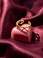 Lundholm Saksun ring met verbonden hartjes goudkleurig op een roze chocolade hartje