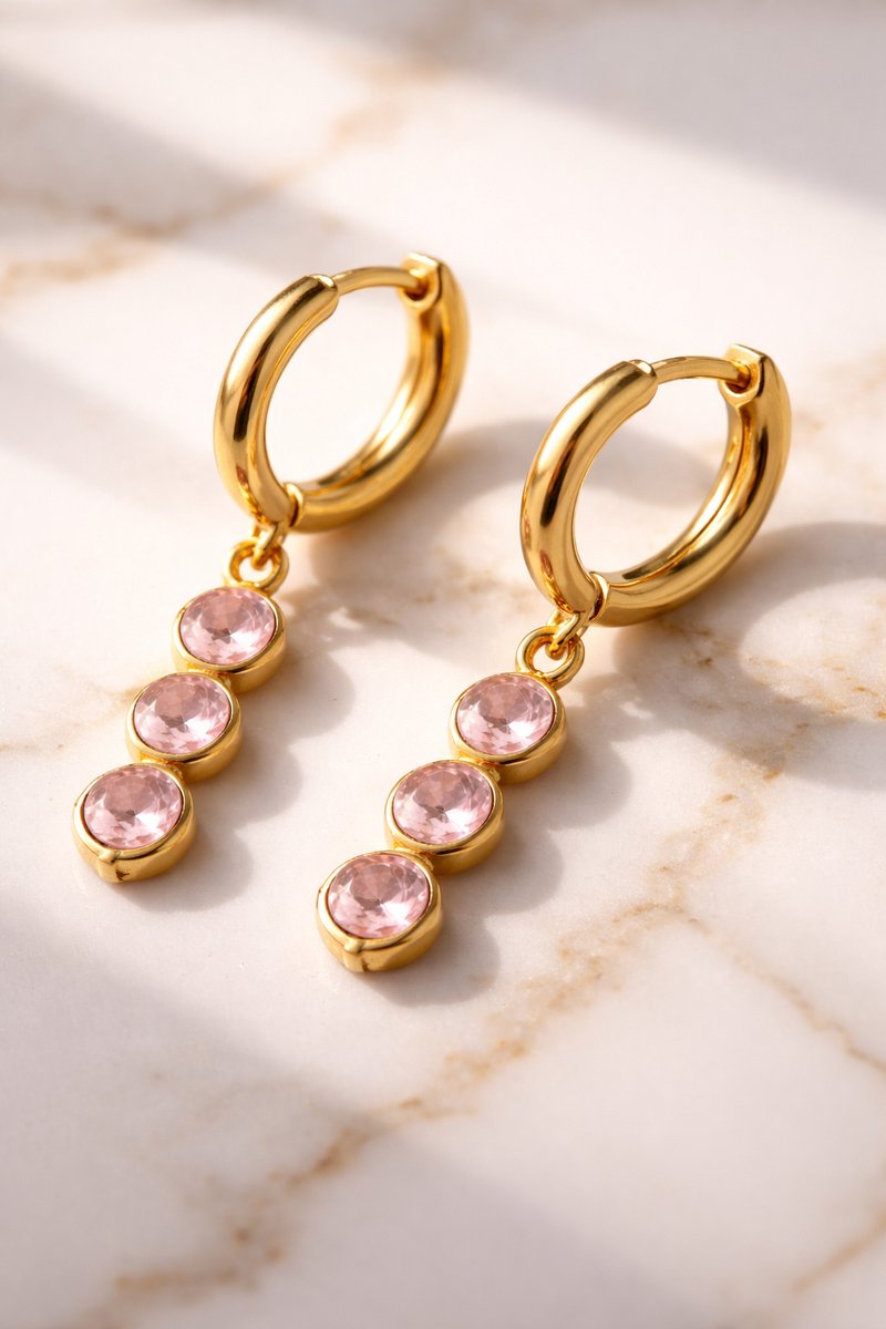 Lundholm Sam creolen oorbellen met roze zirkonia steentjes hangers in goudkleurig op marmer, sfeervolle styling