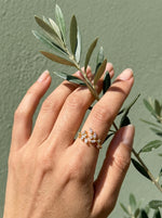 Hand met olijftak en de Lundholm Sanna ring goudkleurig met blaadjes van zirkonia