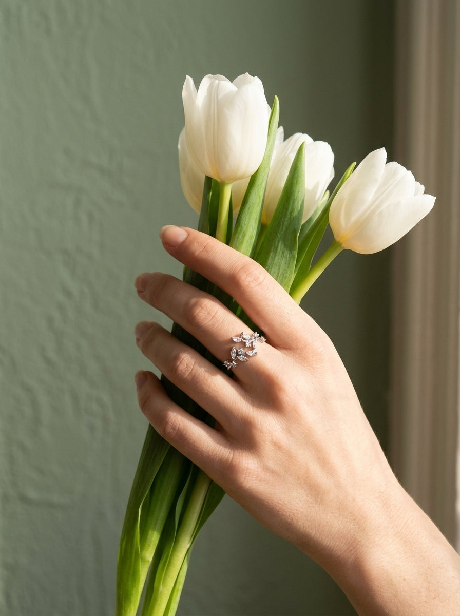 Hand met witte tulpen en de Lundholm Sanna ring zilverkleurig met blad en zirkonia