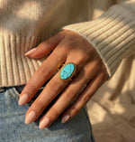 Lundholm Sienna verstelbare cuff ring met blauwe turkoois natuursteen in goudkleurig, gedragen aan vrouwenhand