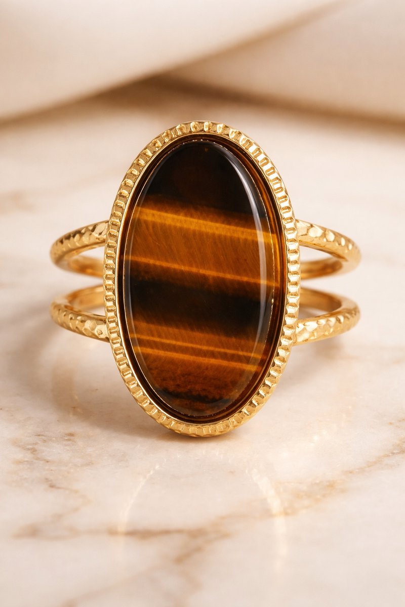 Lundholm Sienna verstelbare statement ring met grote tijgeroog steen in goudkleurig op marmer, productfoto