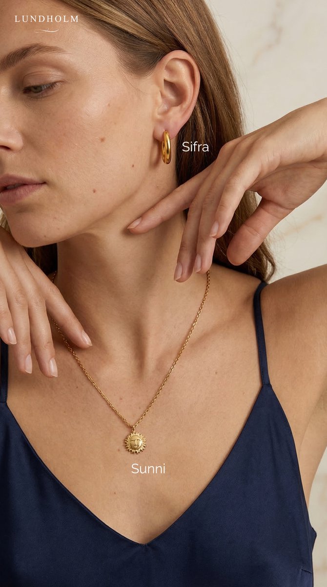 Lundholm Sifra goudkleurige ovale hoepel oorbellen en Sunni ketting met zonhanger gedragen door model, elegante goudkleurige sieradenset