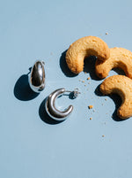 Lundholm Simone chunky halve maan oorringen zilverkleurig naast halvemaanvormige koekjes