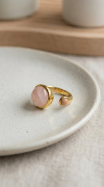 Lundholm Sophia ring met rozenkwarts en zonnesteen roze edelsteen op keramisch schaaltje, goudkleurig 18K verguld stainless steel verstelbare ring lifestyle